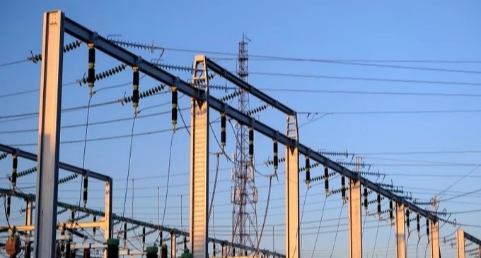 Elektrické vedení a energetická infrastruktura na pozadí zataženého nebe