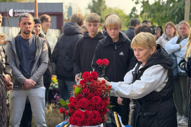 Pessoas com flores perto de um edifício durante a despedida em Sinelnikove