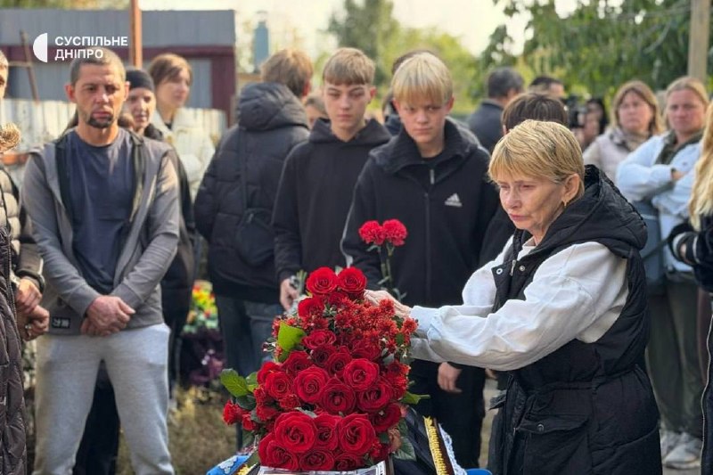 Pessoas com flores perto de um edifício durante a despedida em Sinelnikove
