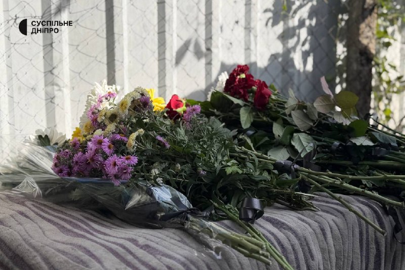 Pessoas com flores perto de um edifício durante a despedida em Sinelnikove
