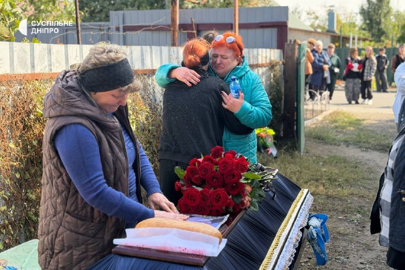 Pessoas com flores perto de um edifício durante a despedida em Sinelnikove