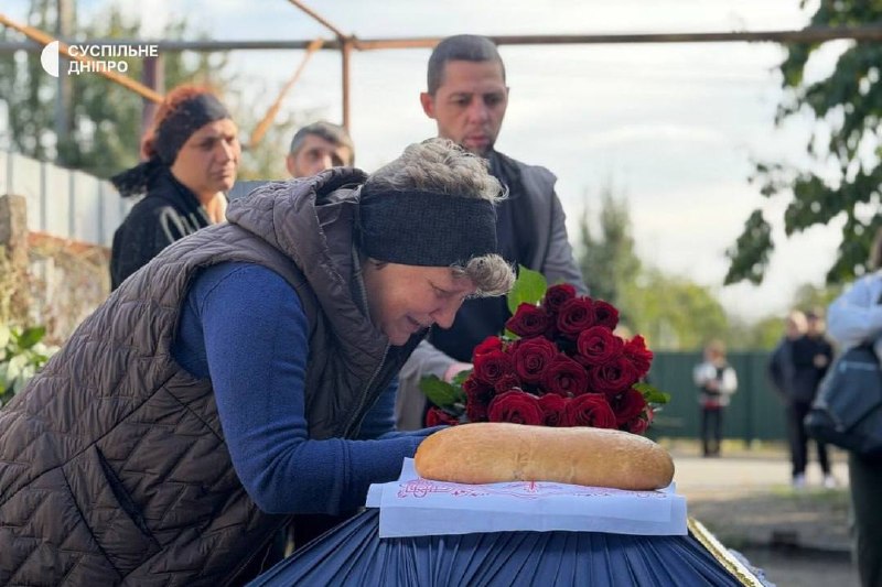 Pessoas com flores perto de um edifício durante a despedida em Sinelnikove