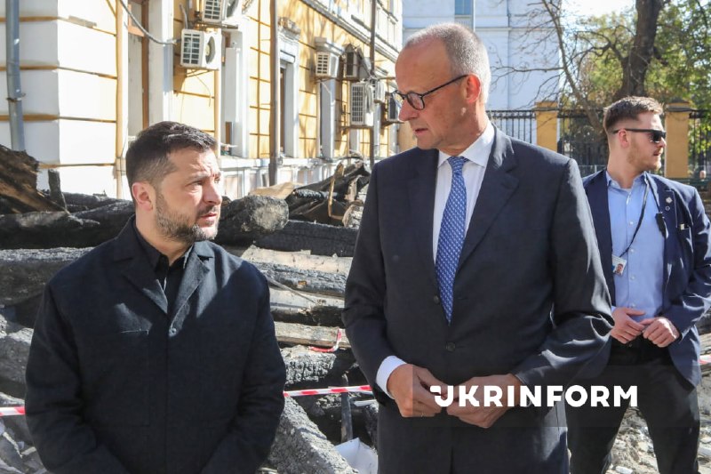 O presidente da Ucrânia e o chanceler da Alemanha observam o edifício destruído da academia de ciências em Kiev