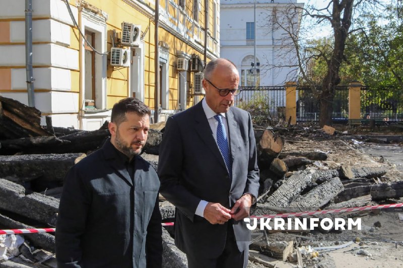 O presidente da Ucrânia e o chanceler da Alemanha observam o edifício destruído da academia de ciências em Kiev