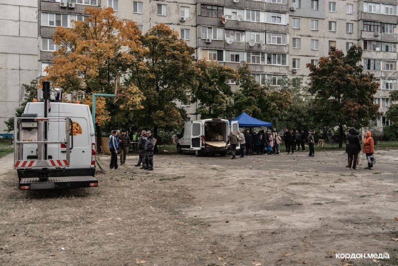 Люди прибирають територію біля житлового будинку після авіаудару